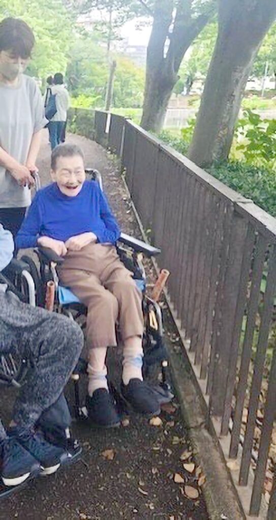 鹿沼公園の木々に囲まれた遊歩道を車椅子で散策する利用者様
