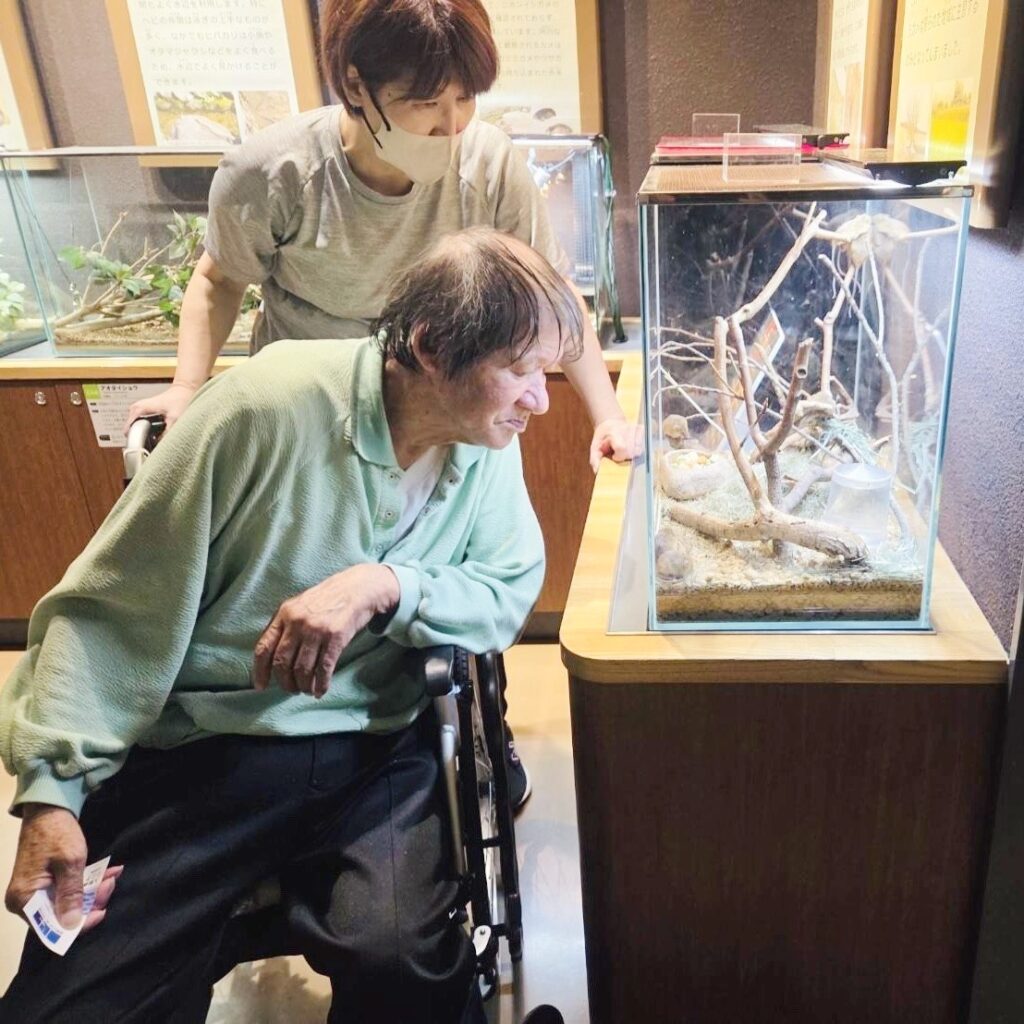 アクアリウムさがみはらで、スタッフと一緒に生き物の展示をのぞき込む車椅子の利用者様